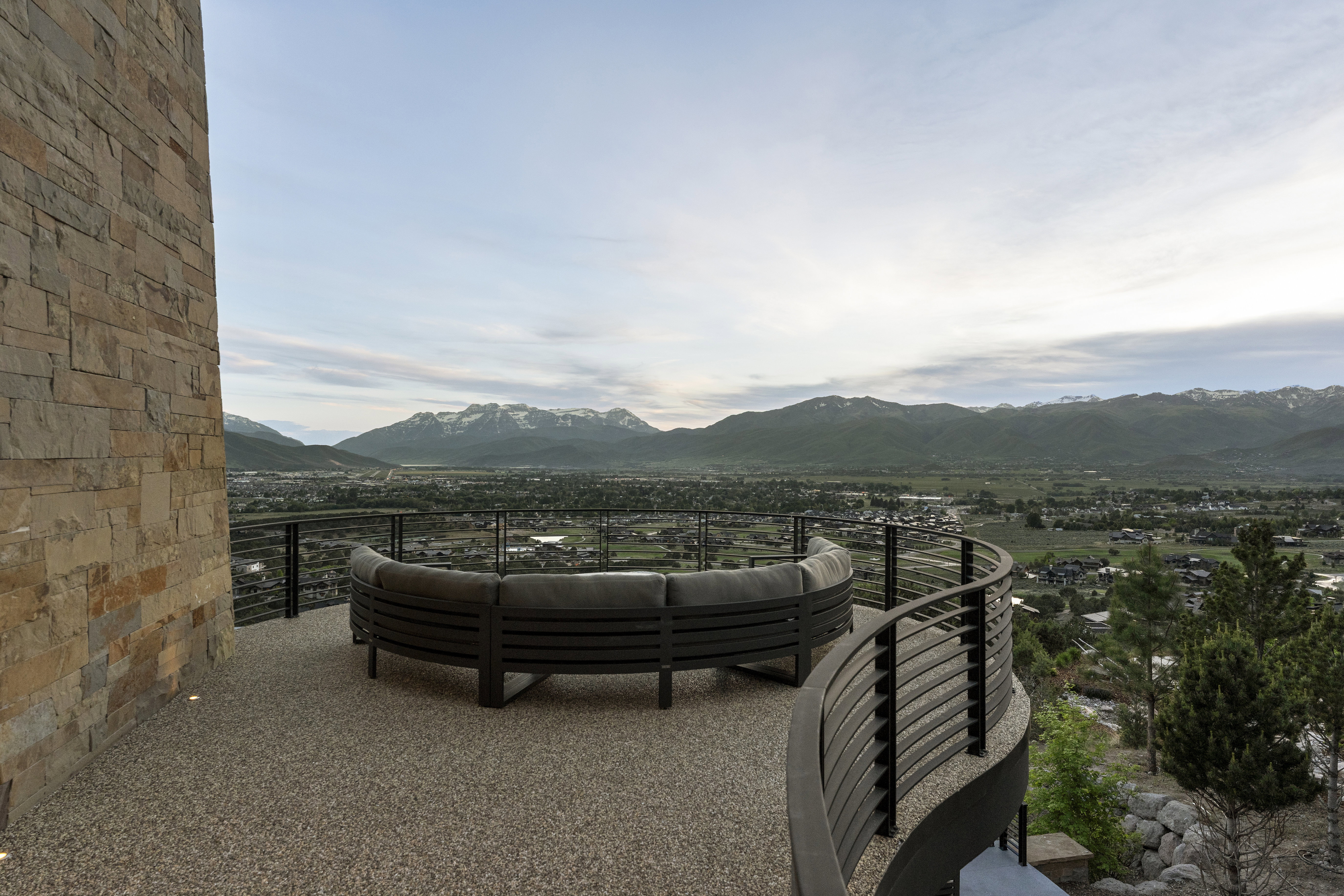 Expansive outdoor patio featuring a stone wall, cable railing, and a textured pebble-aggregate surface