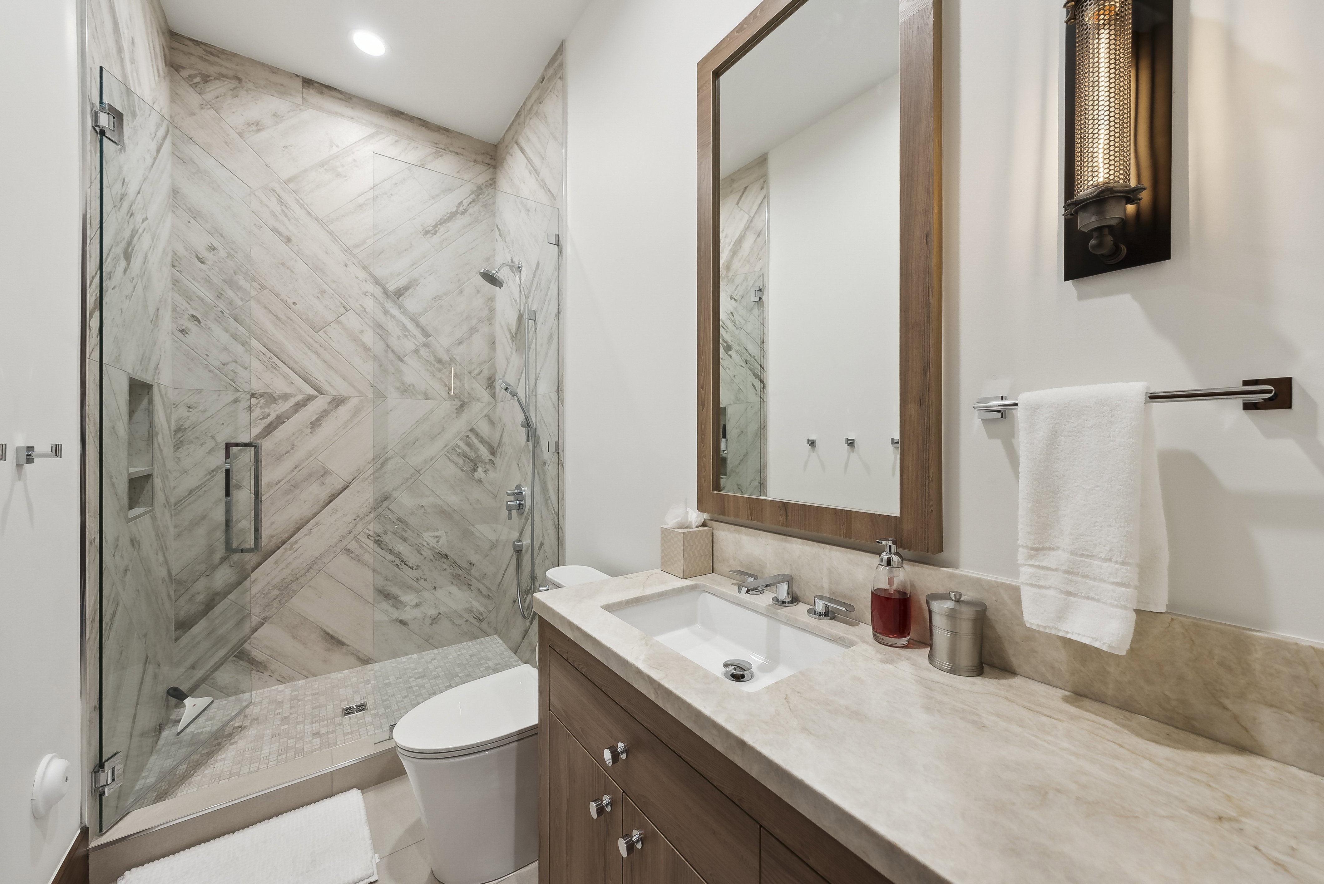 Glass-enclosed shower with patterned tile walls and a built-in niche