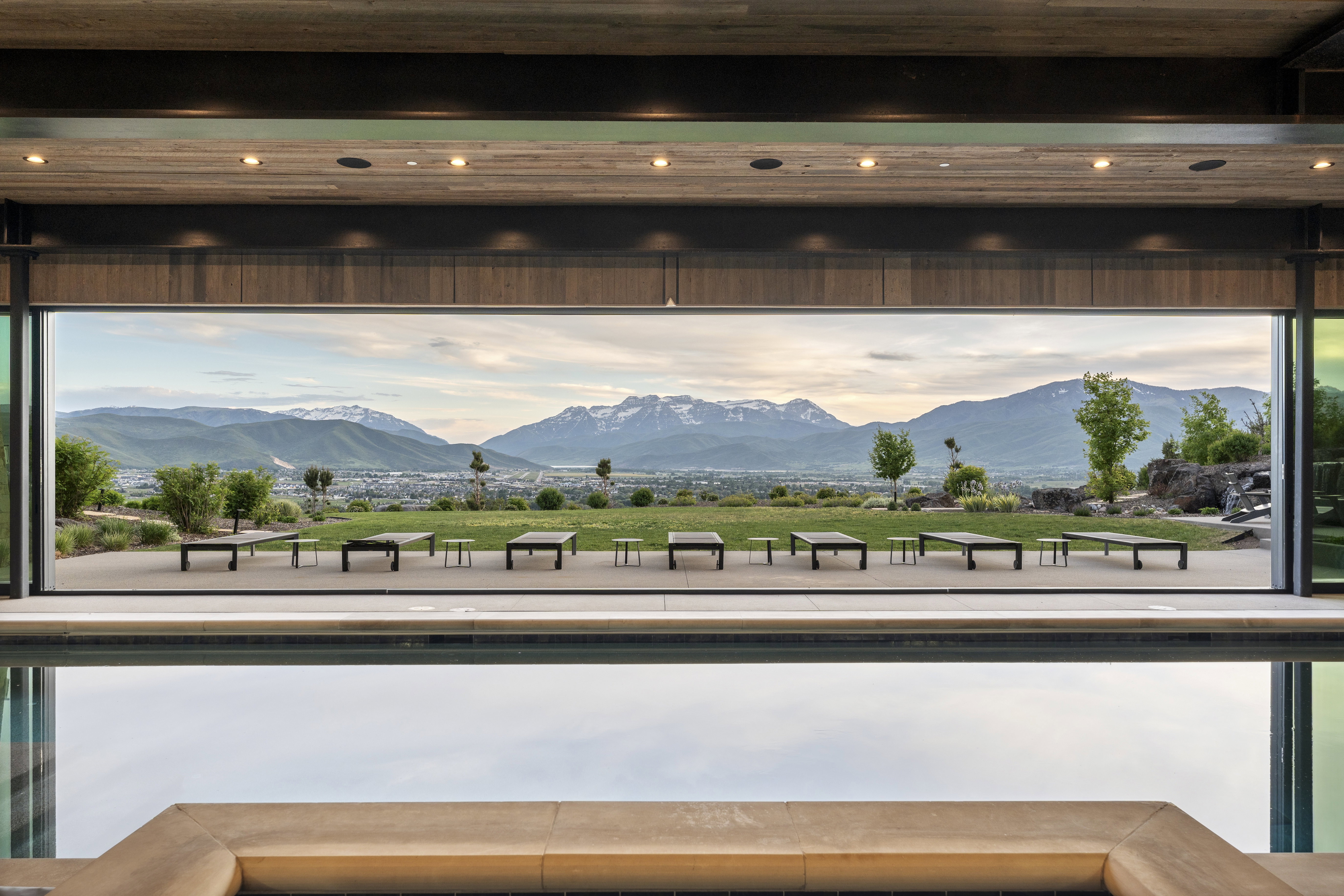 Expansive outdoor living area featuring a large patio, lush green lawn, and distant mountain scenery