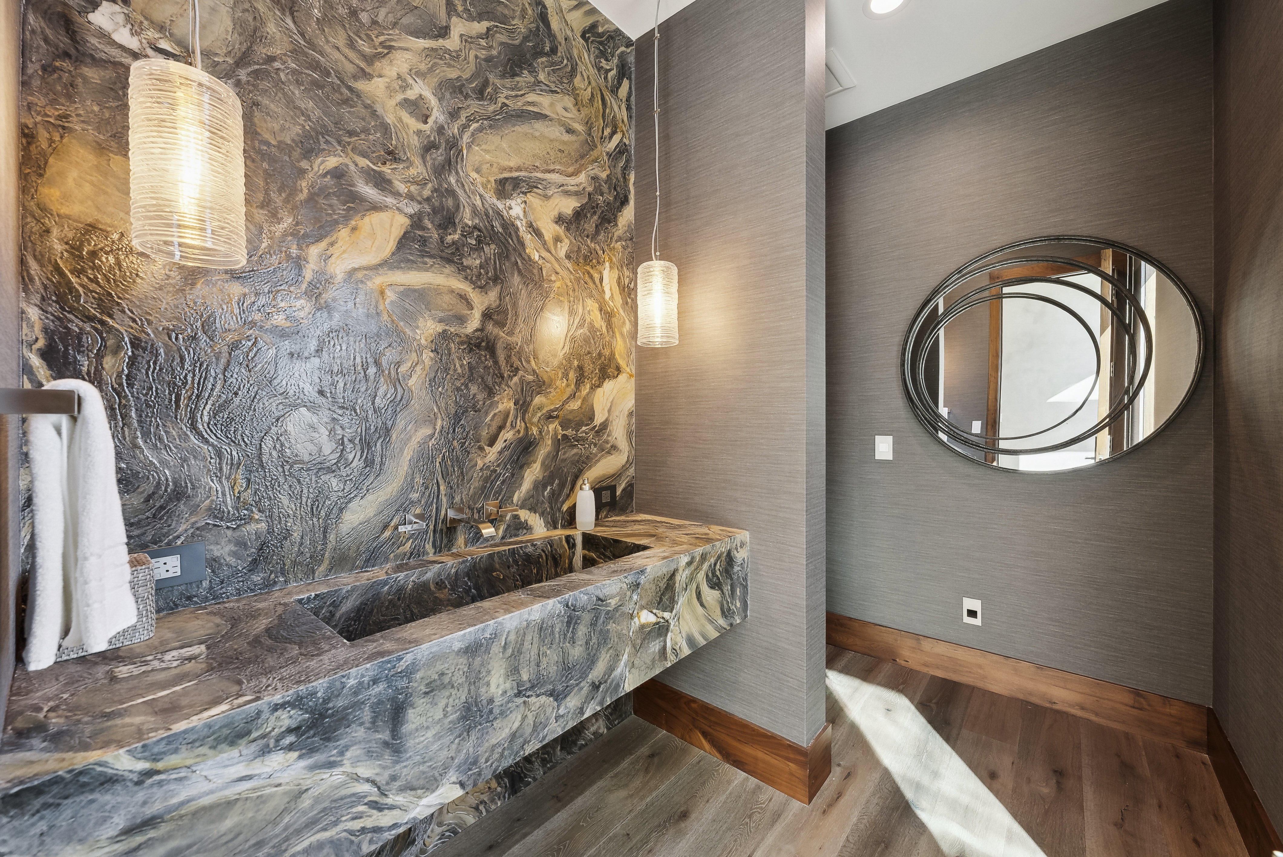 Textured stone accent wall featuring an integrated stone trough sink with wall-mounted faucets