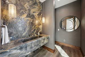 Textured stone accent wall featuring an integrated stone trough sink with wall-mounted faucets