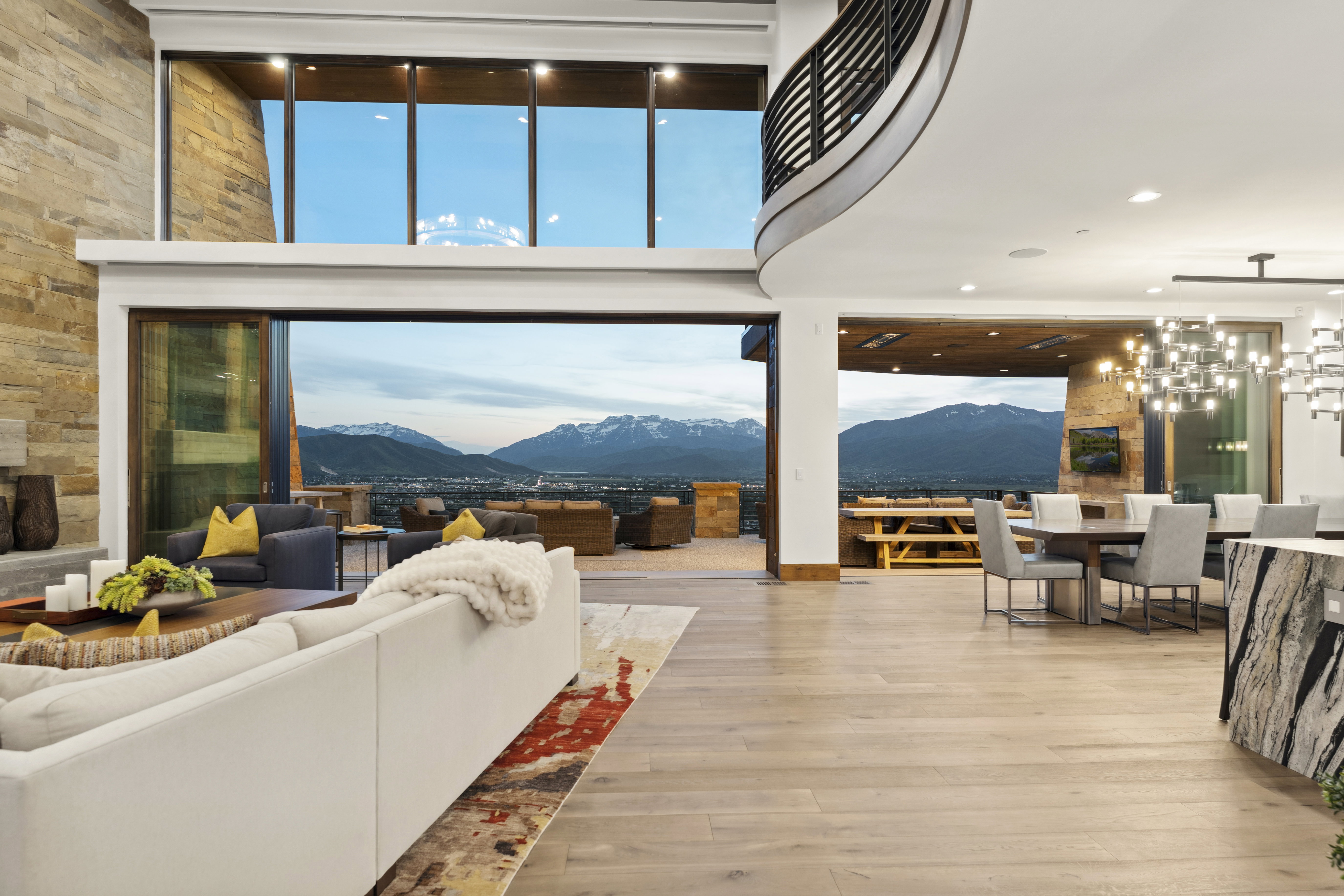 Open-concept living space featuring floor-to-ceiling sliding glass doors, light wood-finish flooring, and a stone accent wall