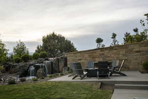 Expansive stone water feature with multiple cascades, surrounded by natural rock landscaping and mature greenery