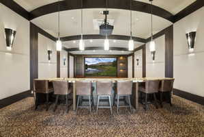 Dedicated media room featuring a large screen display, recessed lighting, and a projector
