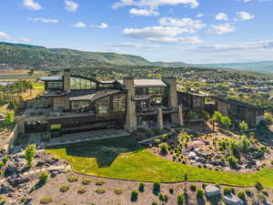 Architectural residence featuring extensive glazing, multiple outdoor terraces, and stone and dark wood-finish cladding