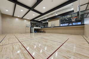 Indoor multi-sport court featuring light wood-finish flooring with marked lines, multiple basketball hoops, and recessed ceiling lighting