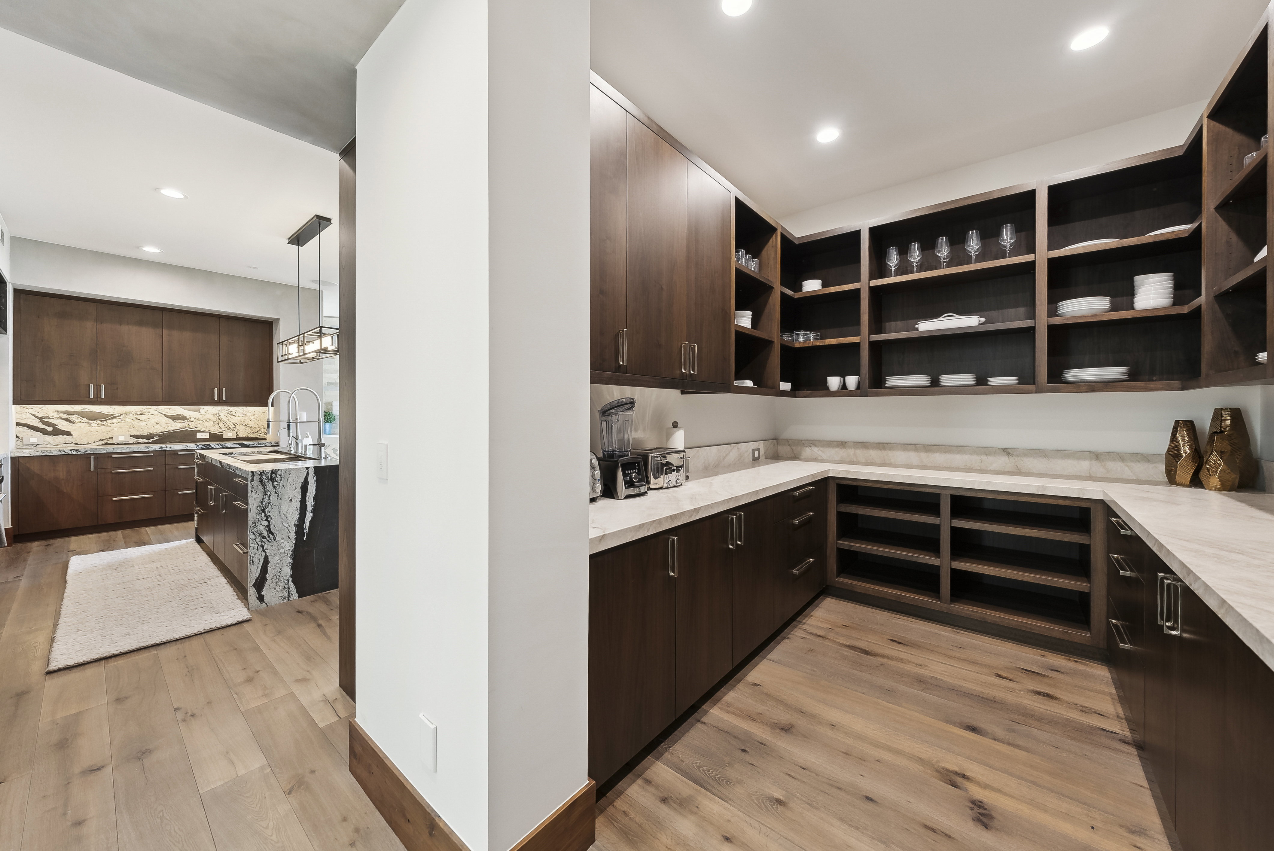 Walk-in pantry featuring extensive wood-finish shelving, perimeter countertops, recessed lighting, and wood-finish flooring
