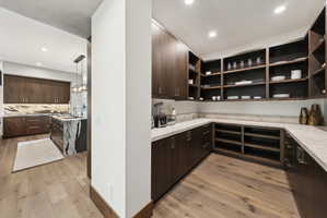 Walk-in pantry featuring extensive wood-finish shelving, perimeter countertops, recessed lighting, and wood-finish flooring