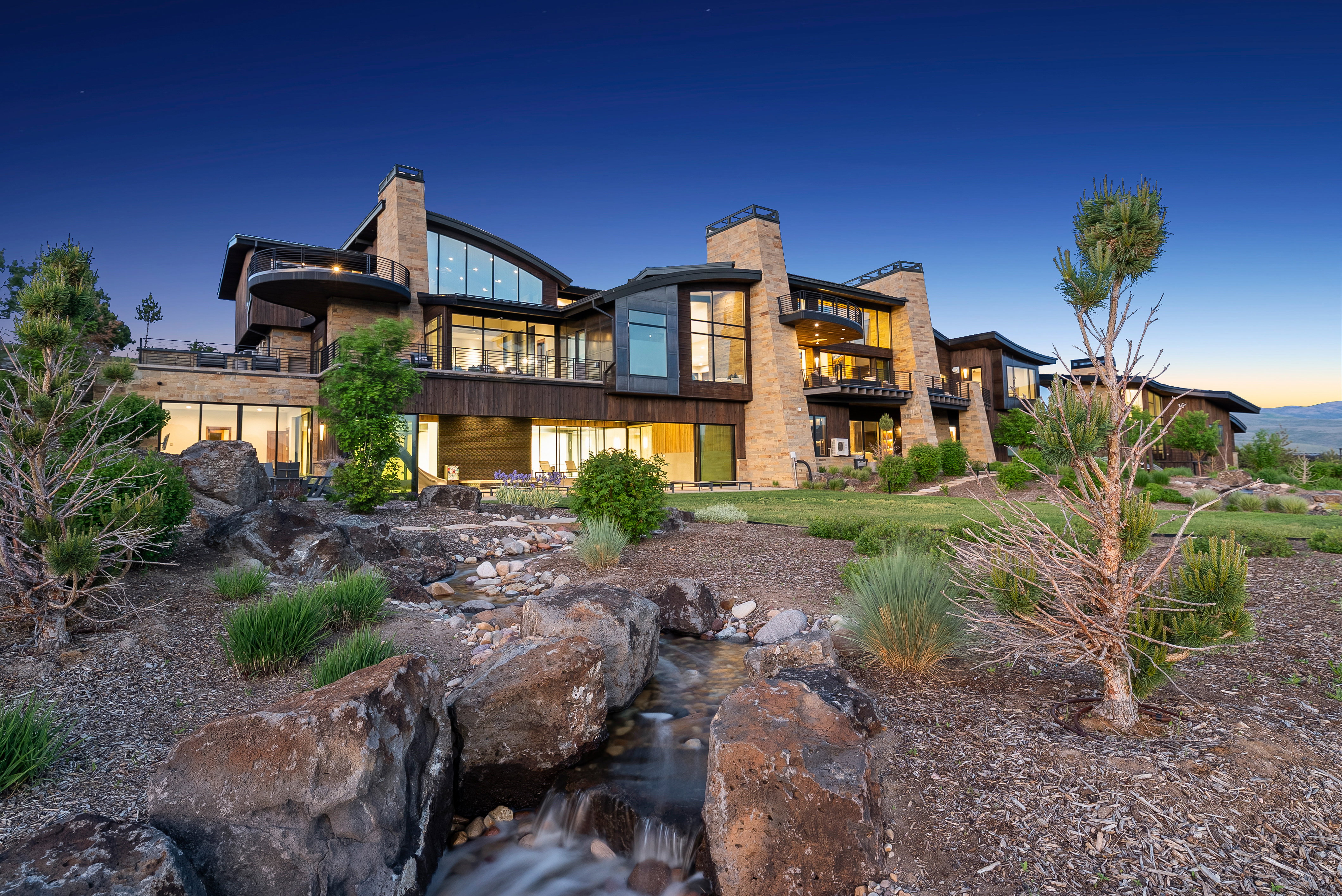 Contemporary multi-level residence featuring stone and wood siding, extensive glazing, and multiple outdoor terraces