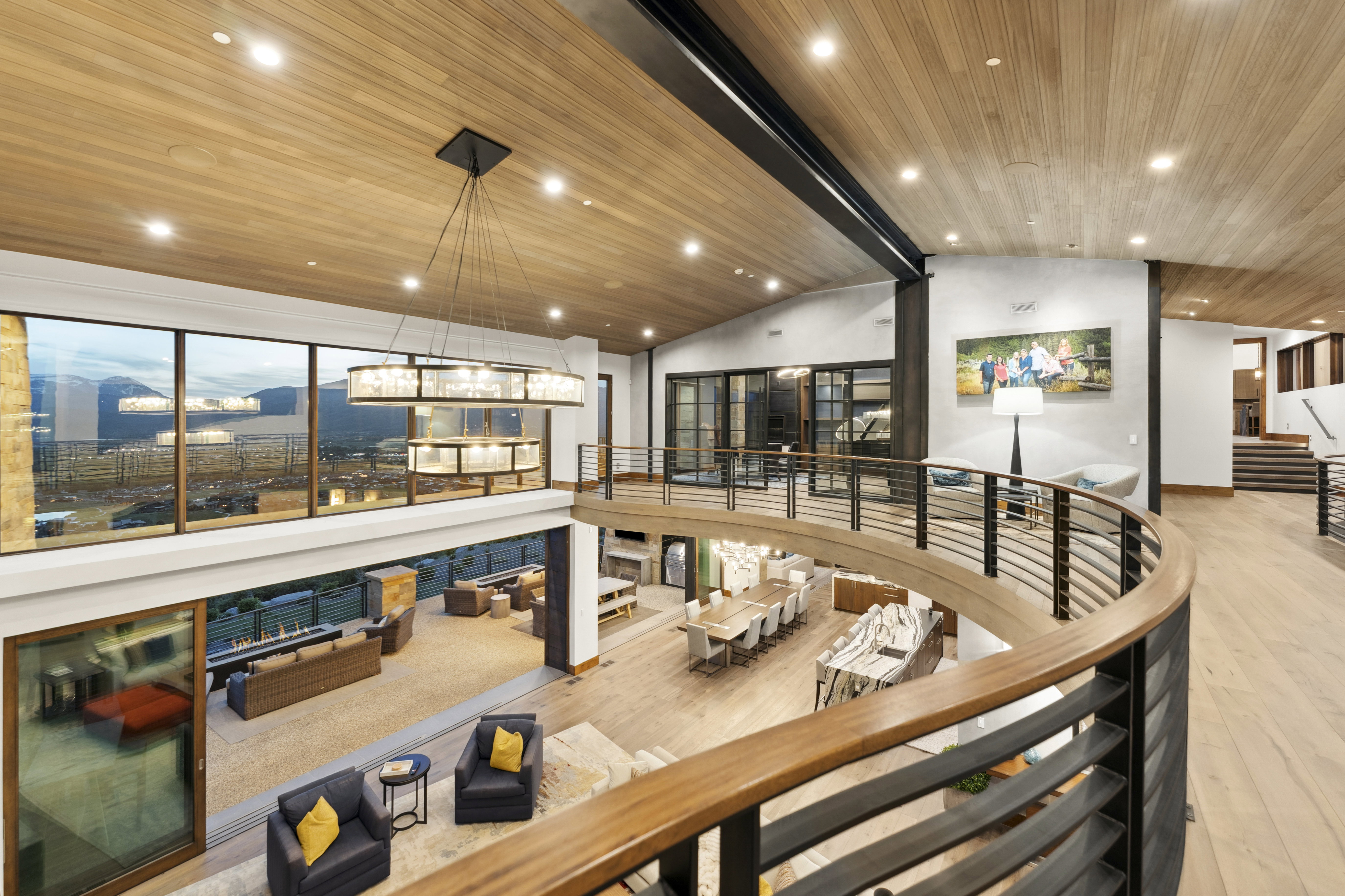 Two-story interior featuring a curved balcony with wood and metal railings, wood plank ceilings, and recessed lighting