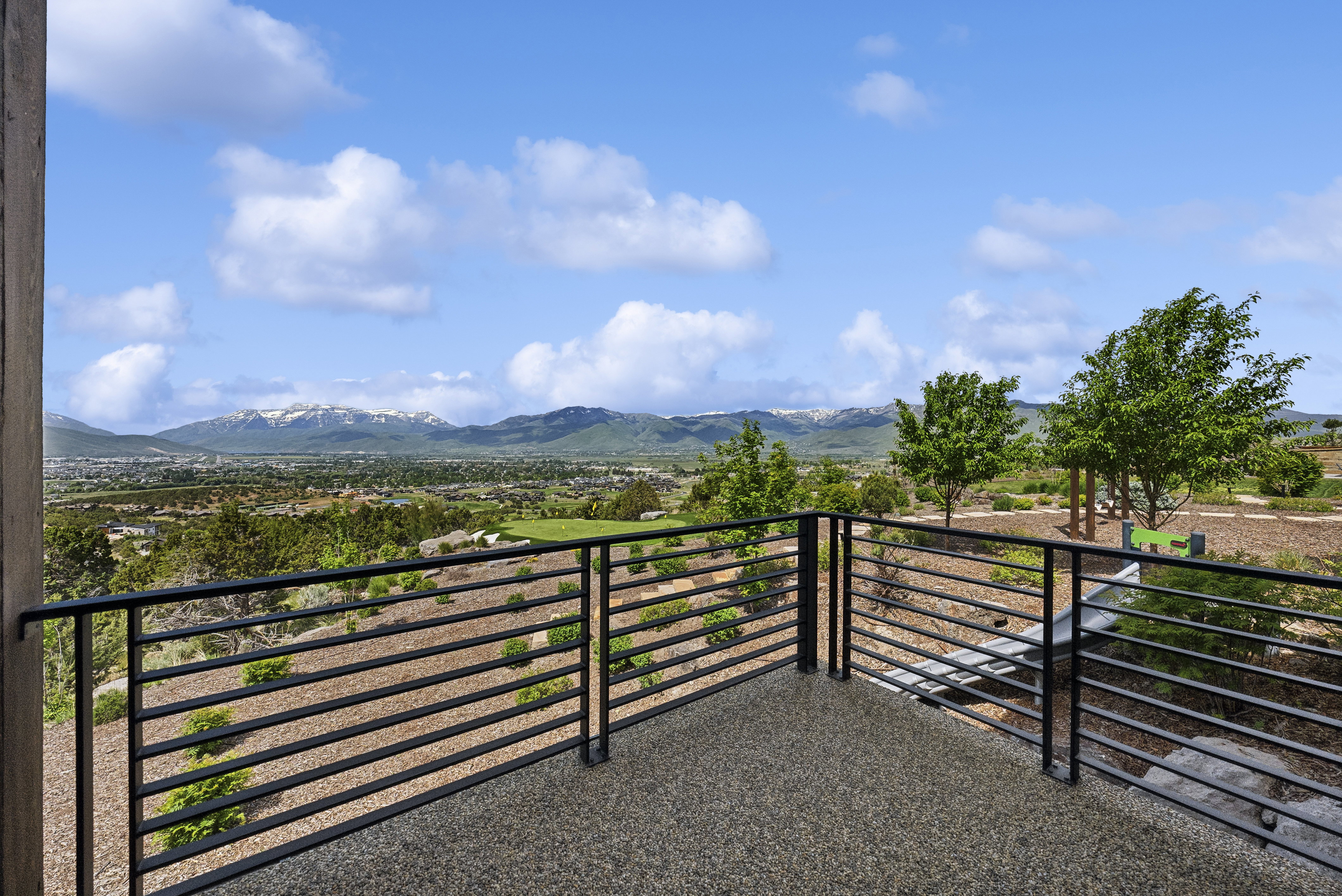 Expansive outdoor balcony featuring a speckled aggregate floor and horizontal metal railing