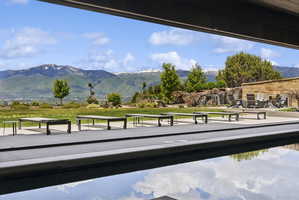 Outdoor entertainment area featuring a dark-tiled pool with a concrete surround, a stone water feature, and a paved patio area