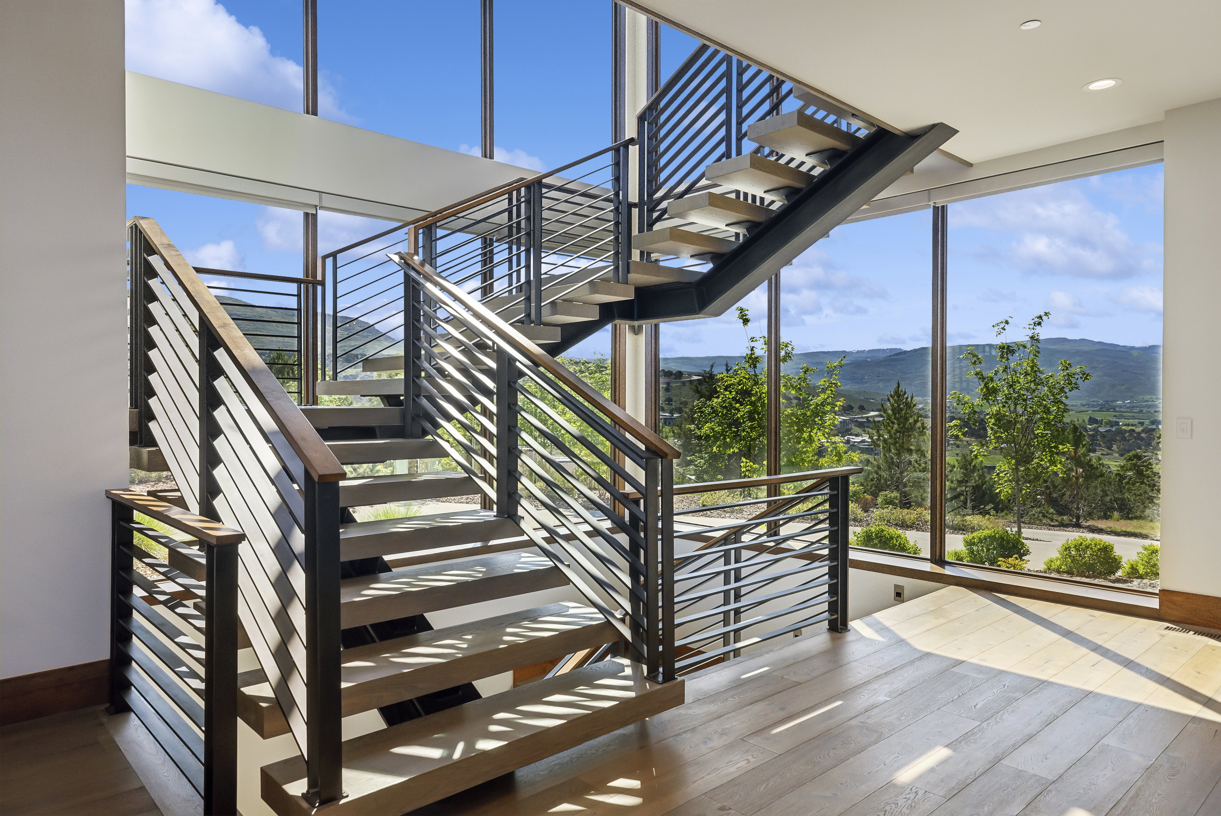 Striking modern staircase with horizontal metal railings and wood-finish handrails