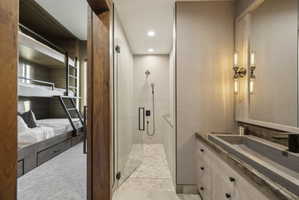 Bathroom with a contemporary vanity featuring a concrete vessel sink and a wall-mounted faucet