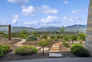 Landscaped outdoor area featuring a natural stone pathway, established plantings, ground-level lighting, and distant mountain scenery