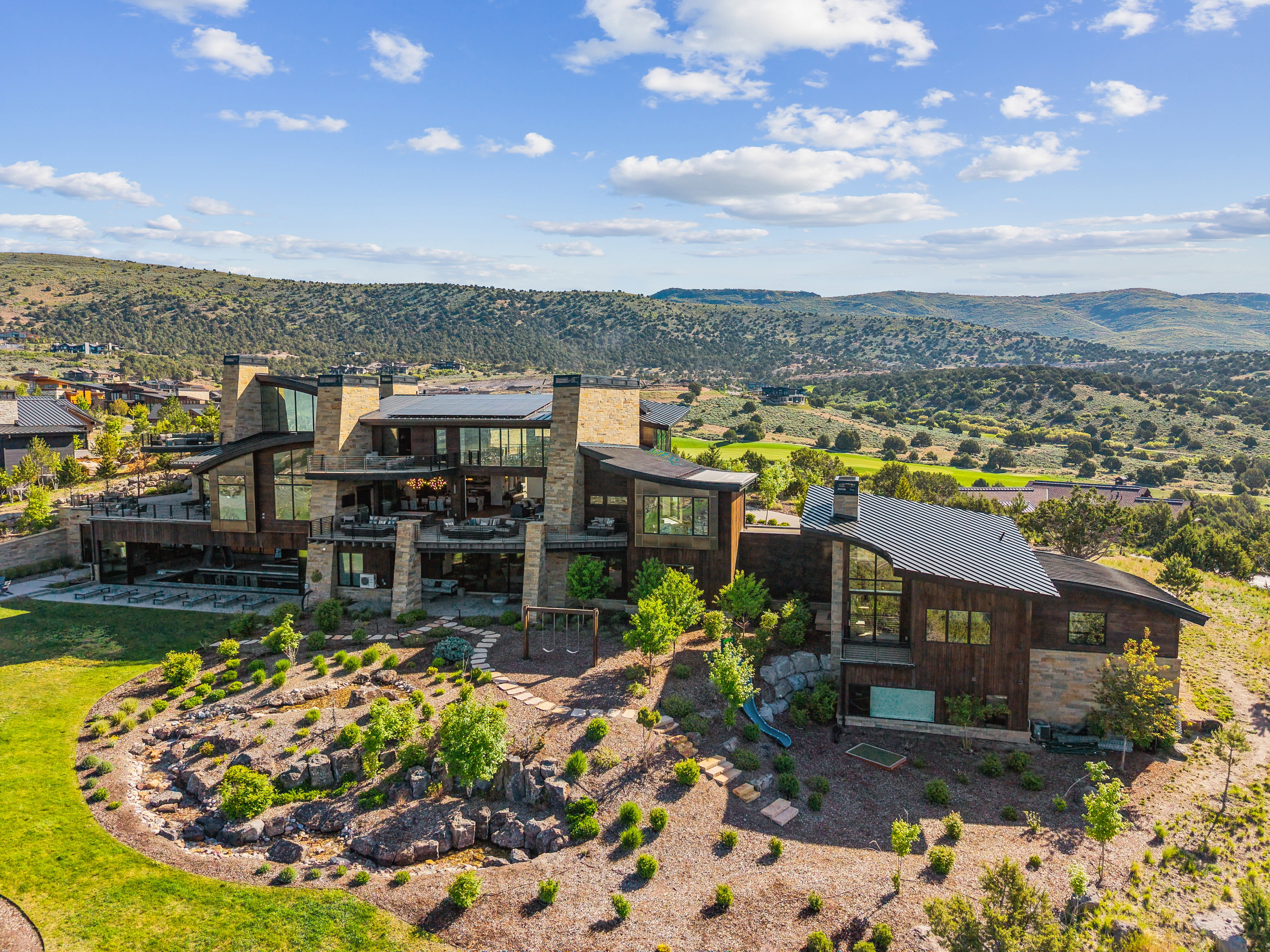 Contemporary multi-level residence featuring extensive stone and wood-paneled exterior finishes