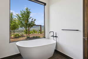 Freestanding soaking tub with matte black fixtures, set against a large picture window