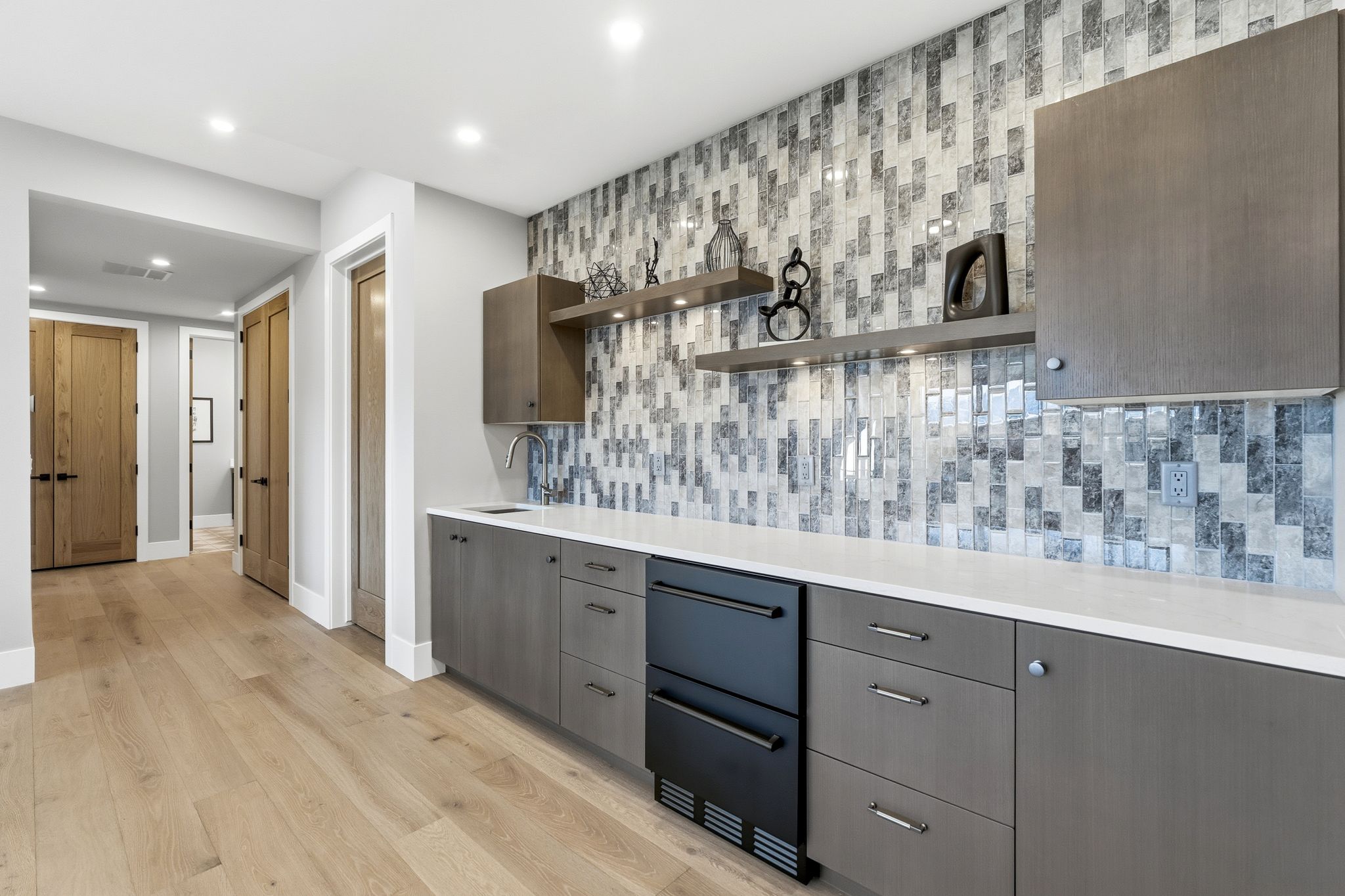 Wet bar featuring a mosaic tile backsplash, integrated under-counter refrigerator, and white countertop
