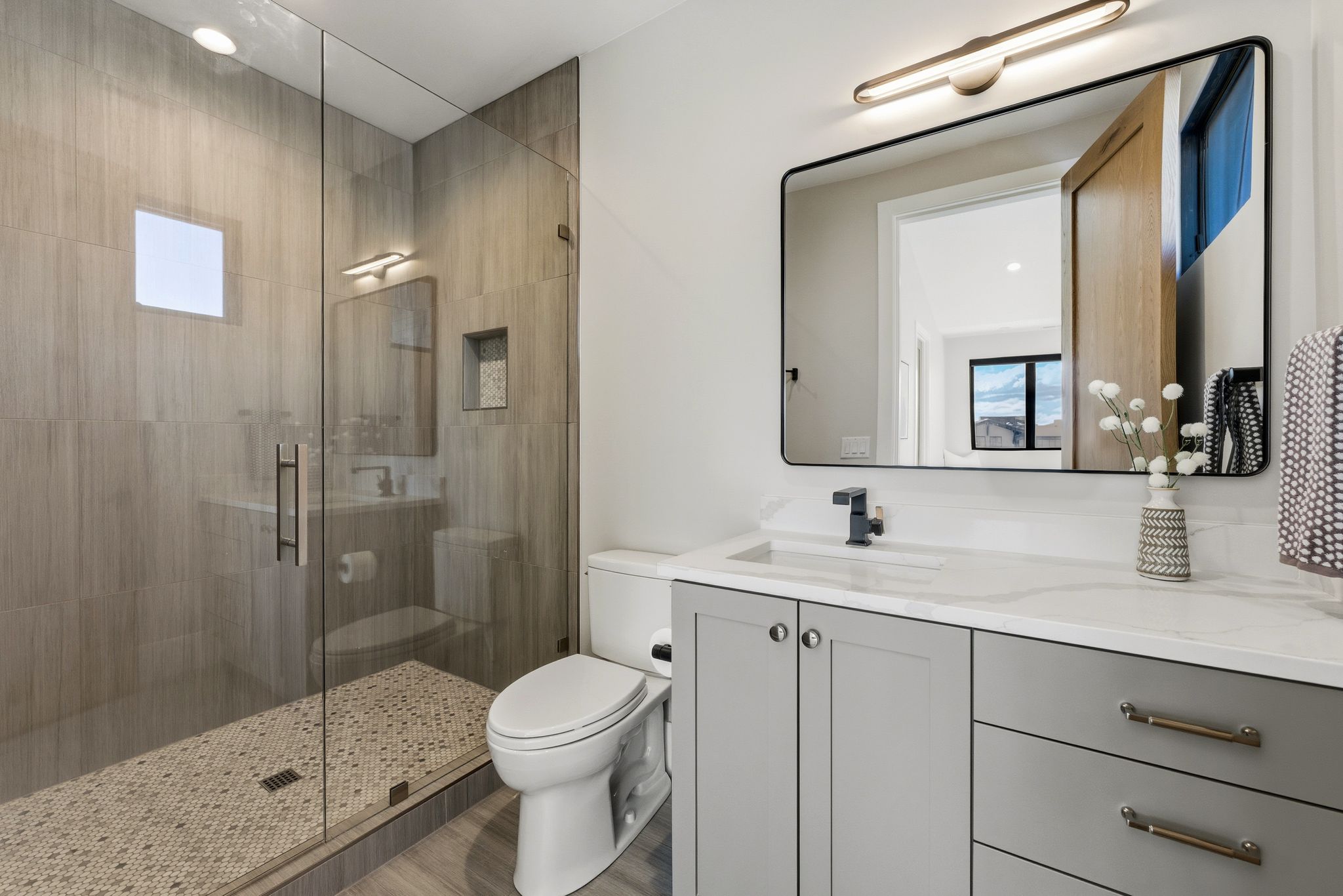 Bathroom featuring a glass-enclosed shower with tile surround, a built-in shower niche, and a mosaic tile floor