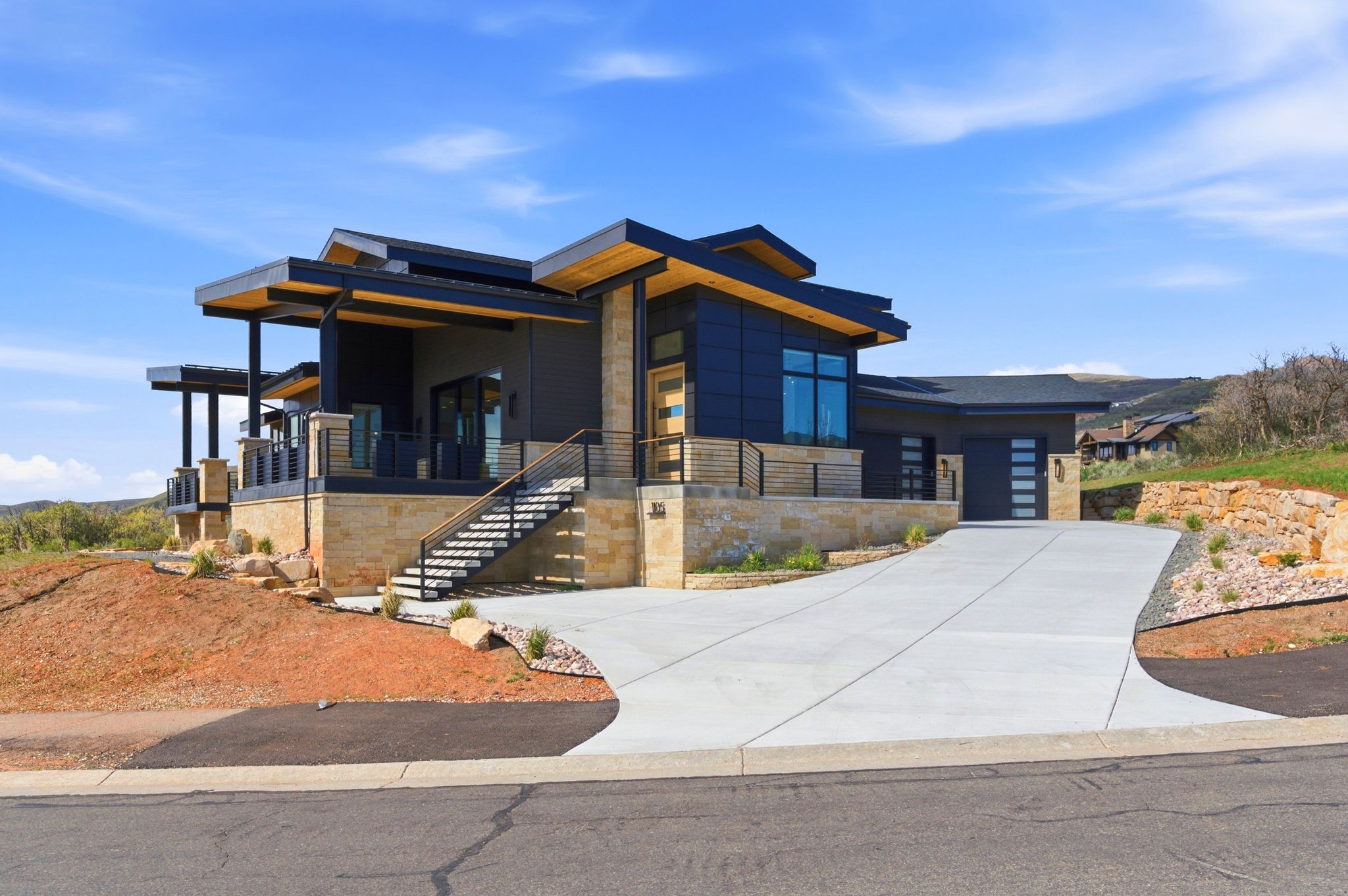 Contemporary architectural design featuring dark siding, stone accents, and expansive windows