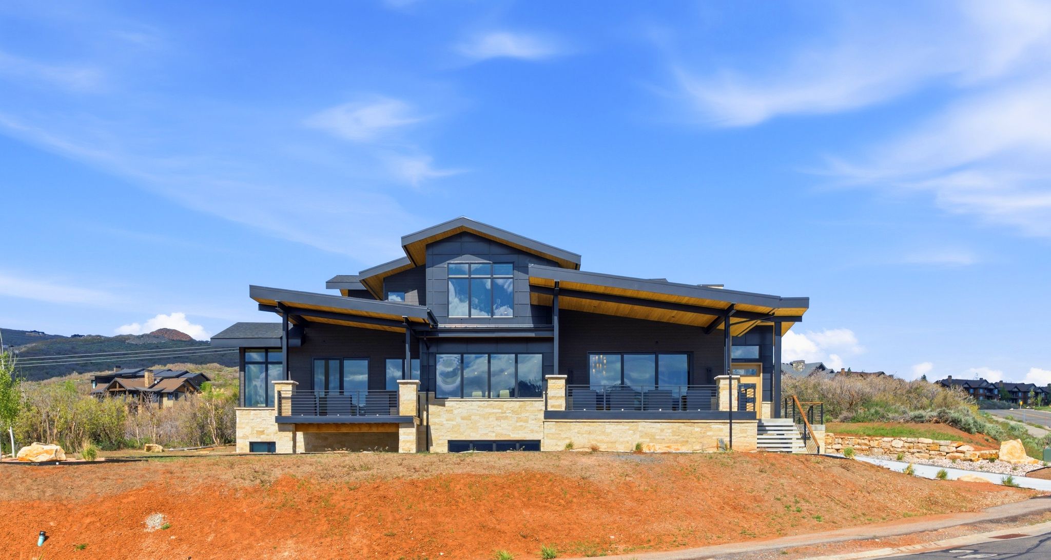 Contemporary architectural design featuring a multi-level structure with stone and dark siding accents