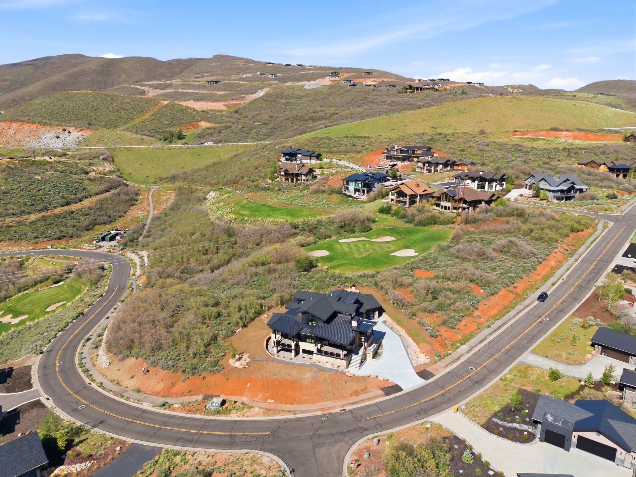 Modern architectural residence with a dark roofline, stone accents, and a large concrete driveway
