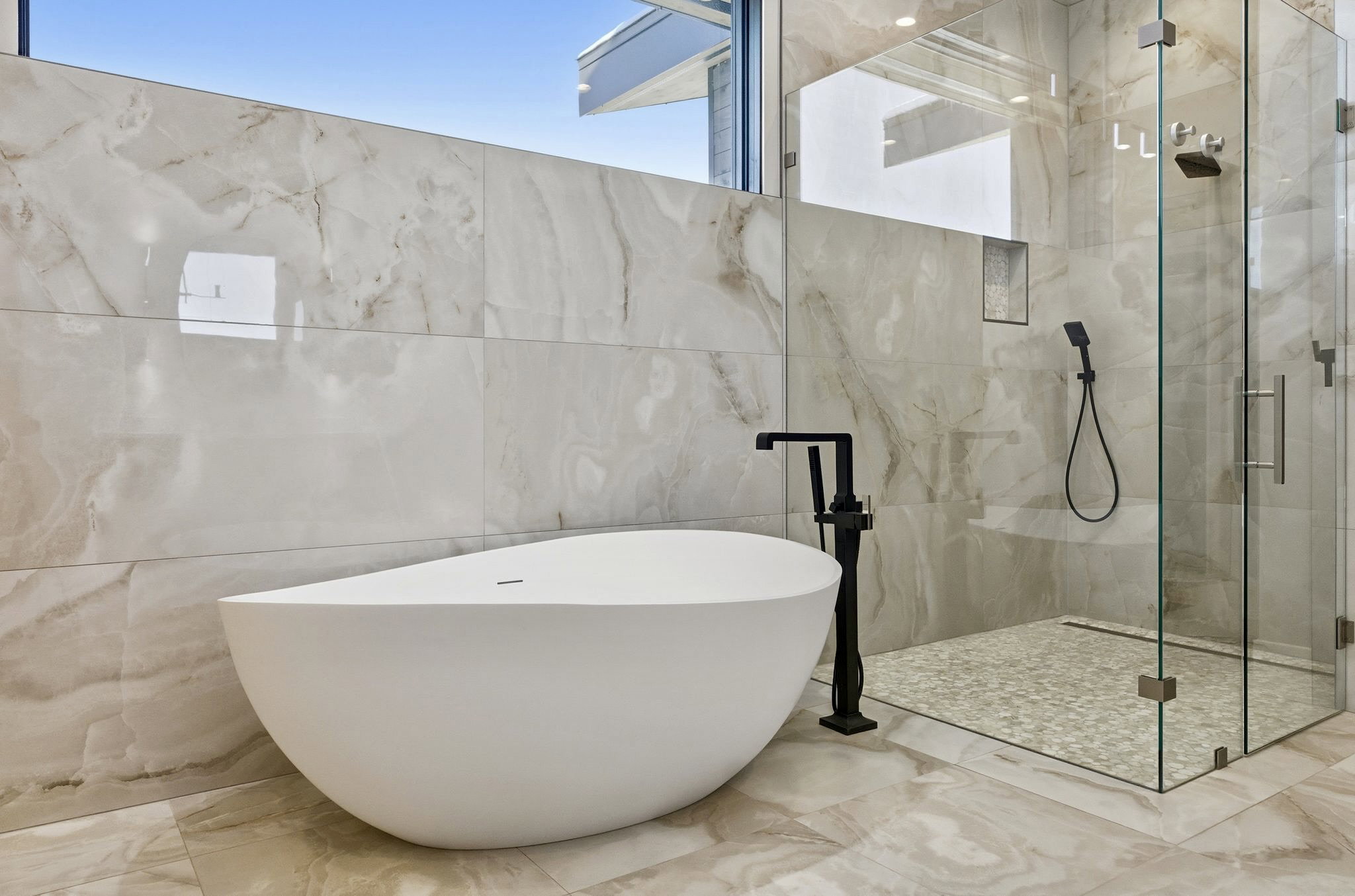 Freestanding soaking tub with matte black floor-mounted faucet