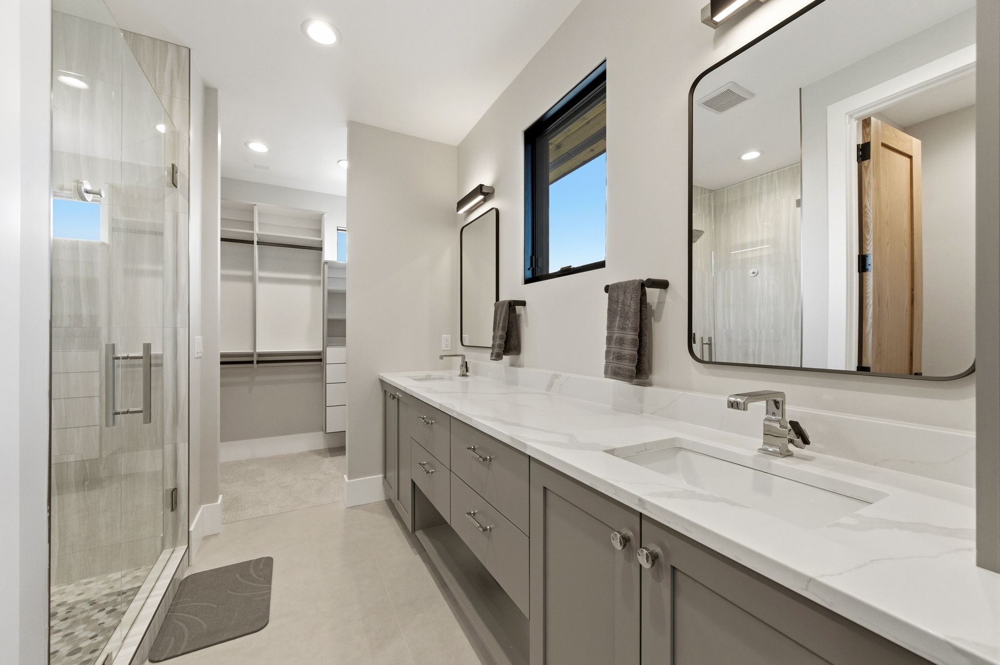 Modern bathroom featuring a dual vanity with white countertops, integrated sinks, and gray cabinetry