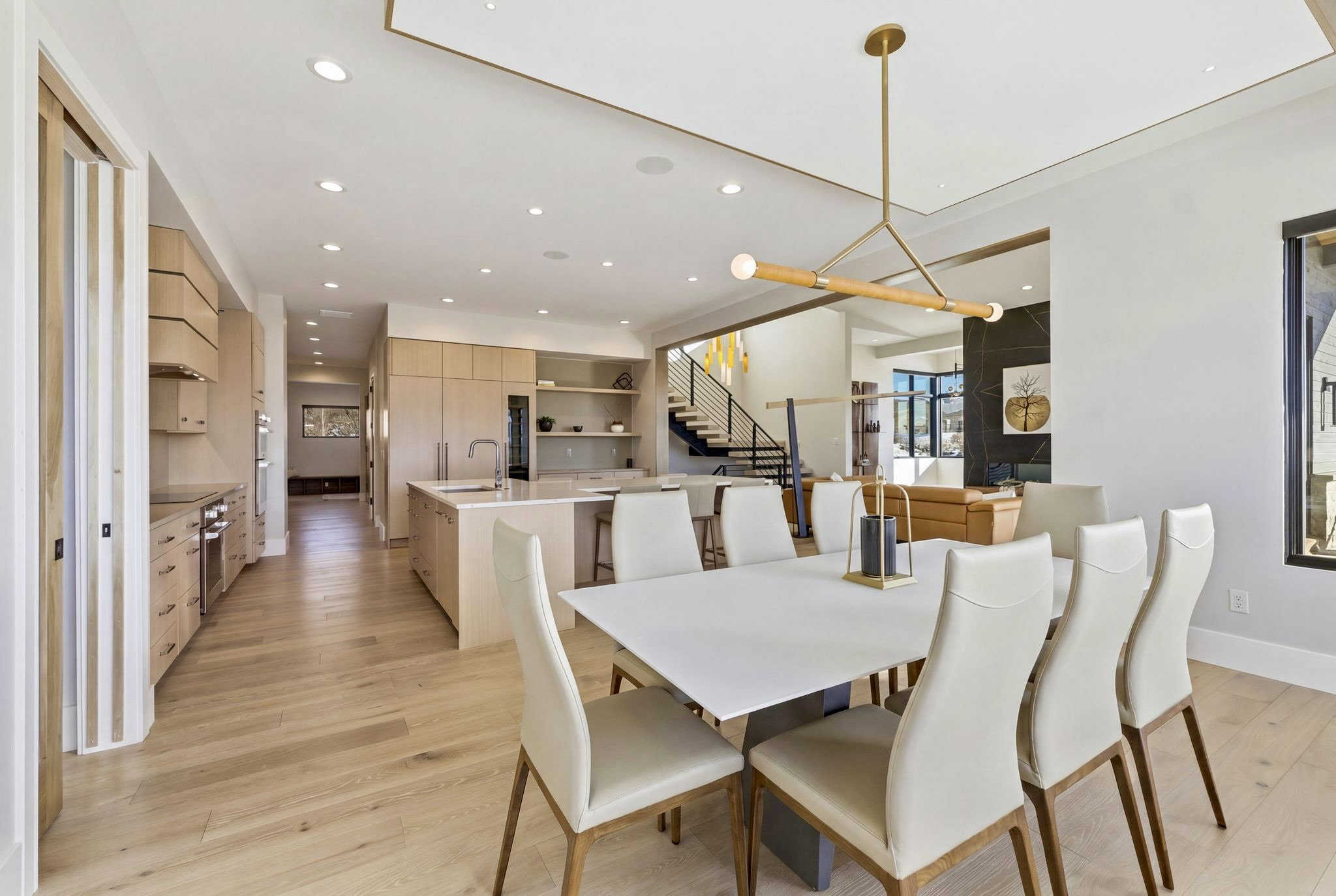 Open-concept dining area with recessed lighting, an architectural linear chandelier, and wood-finish flooring extending into the kitchen