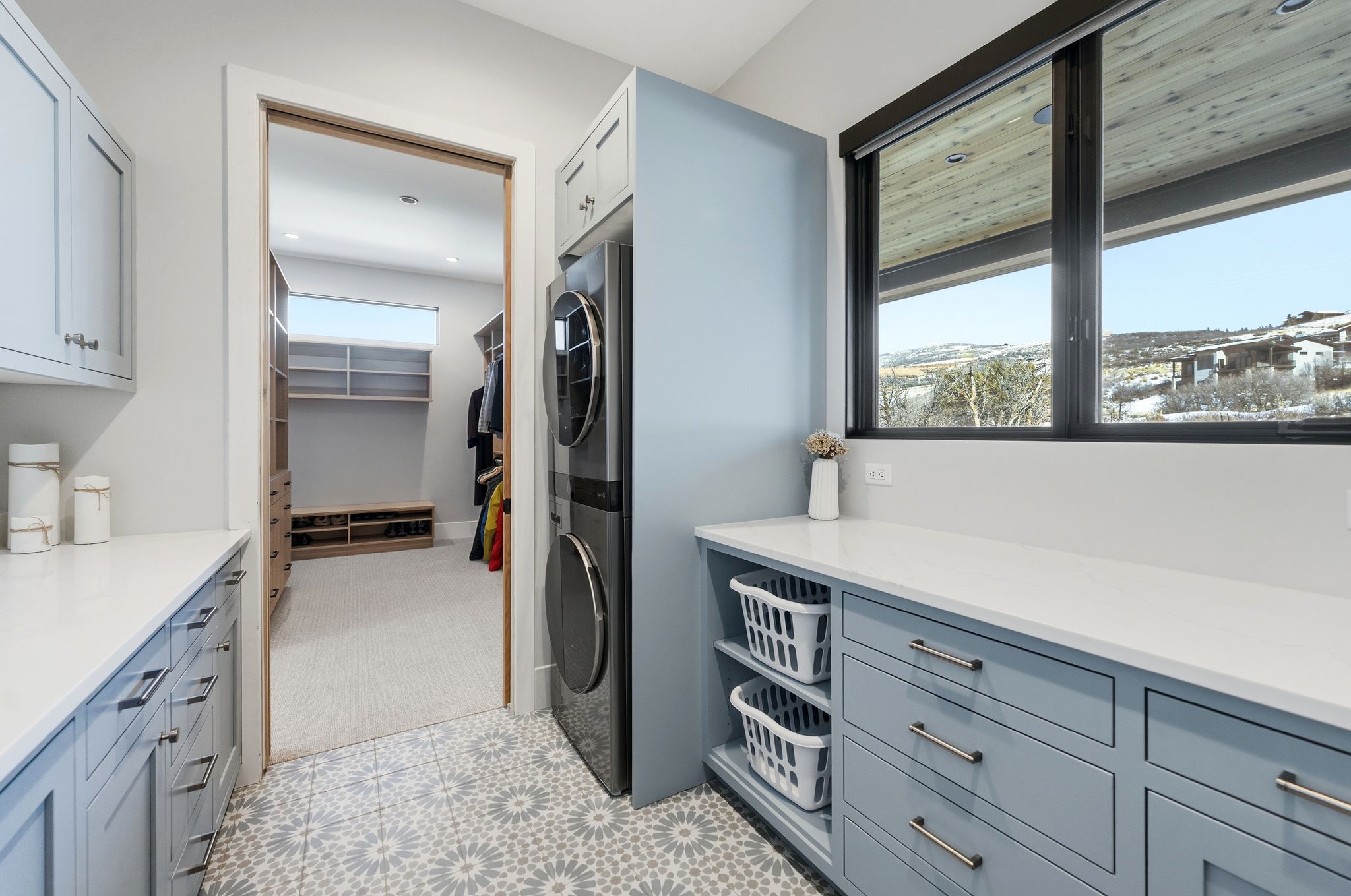 Laundry area with patterned floor tiles, light blue cabinetry, and white countertops