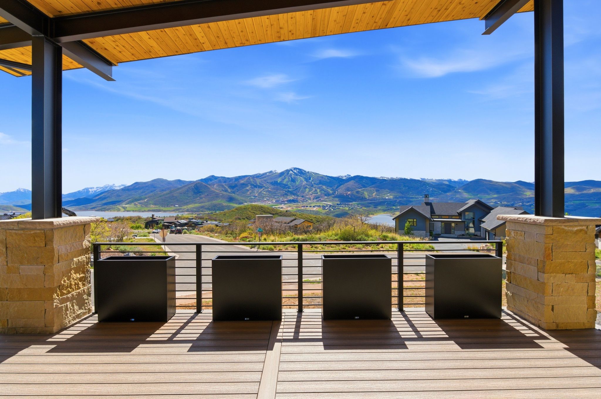 Spacious outdoor deck with wood-finish flooring, a wood-paneled ceiling, and structural steel beams