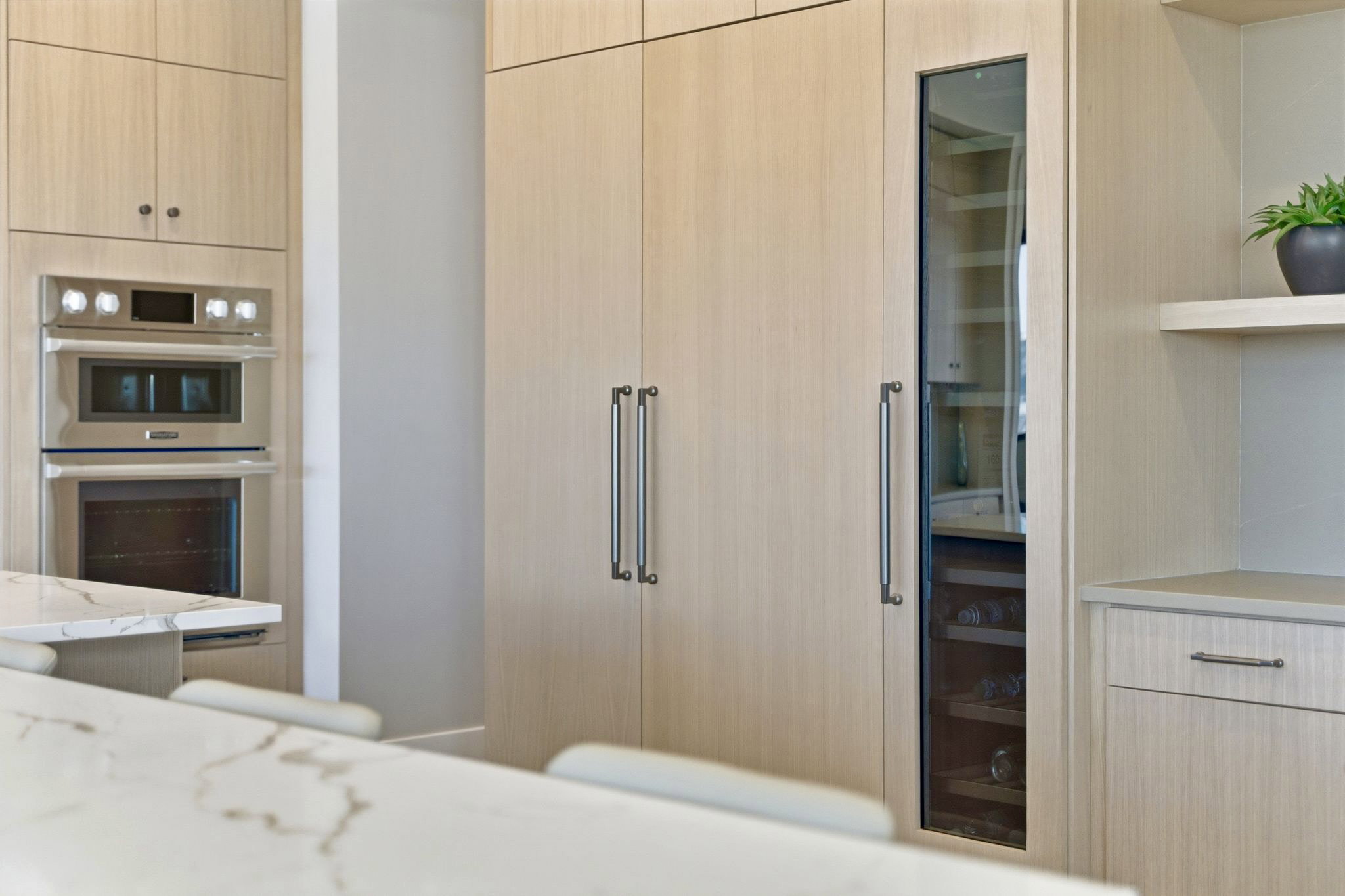 Integrated double ovens and built-in wine refrigeration within custom wood-finish cabinetry
