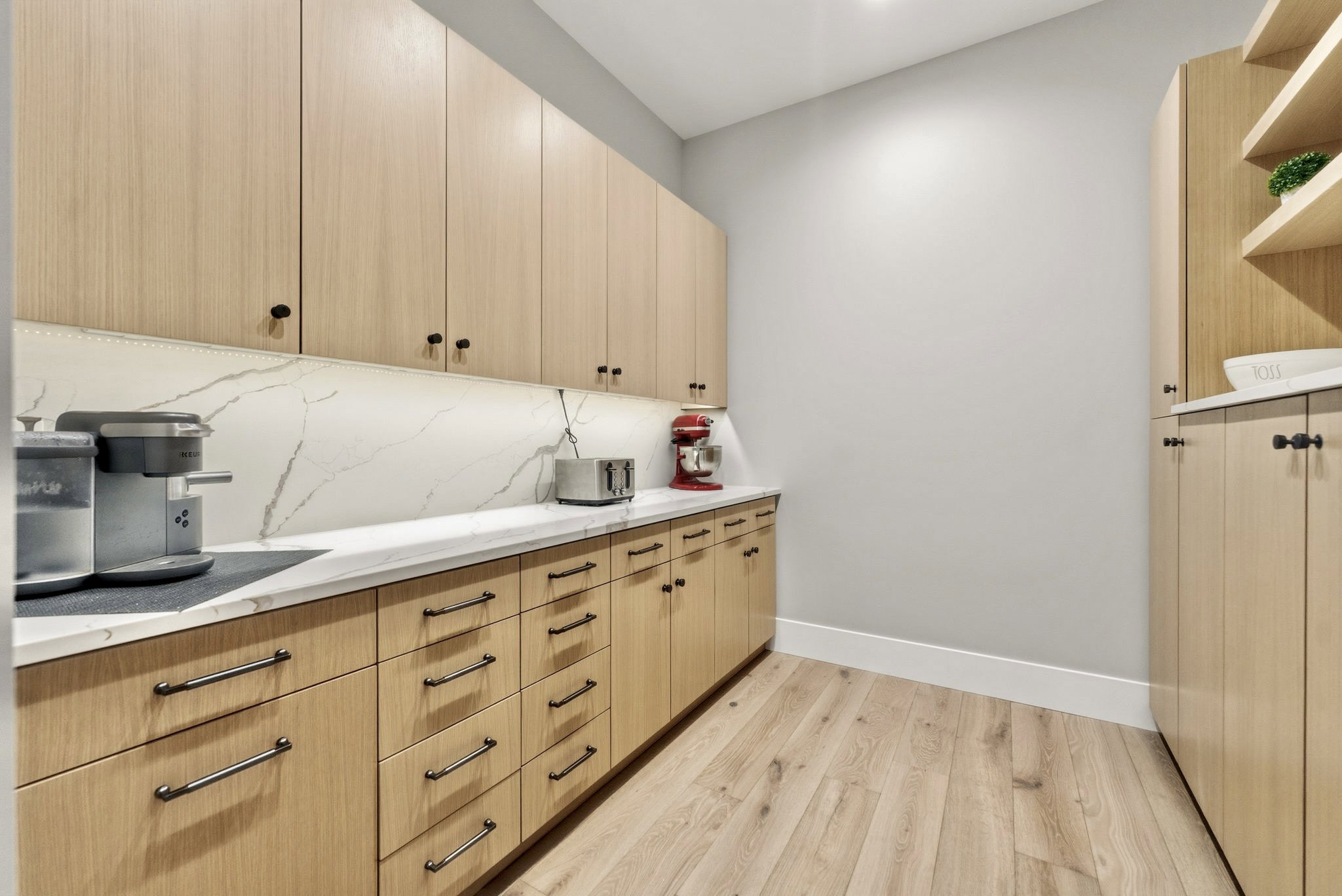 Full-height light wood-finish cabinetry, white countertop, and a corresponding full-height backsplash