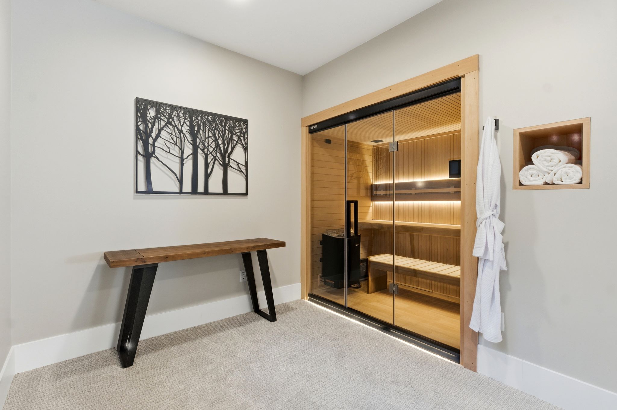 Dedicated sauna room featuring a glass-front cedar sauna with built-in bench seating and a contemporary sauna heater