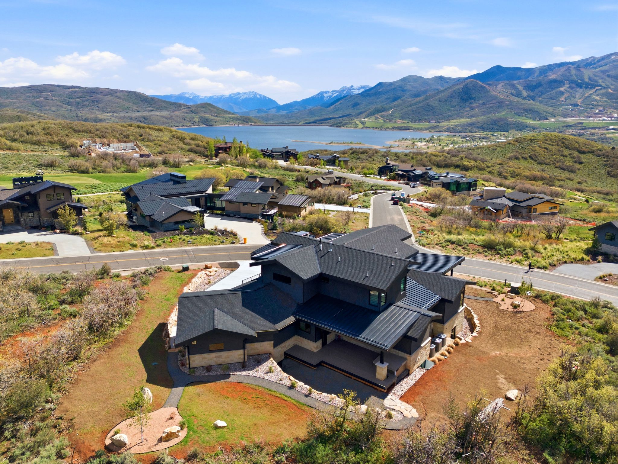 Contemporary architectural design featuring a multi-level roofline, stone and dark-toned siding, and surrounding natural landscaping