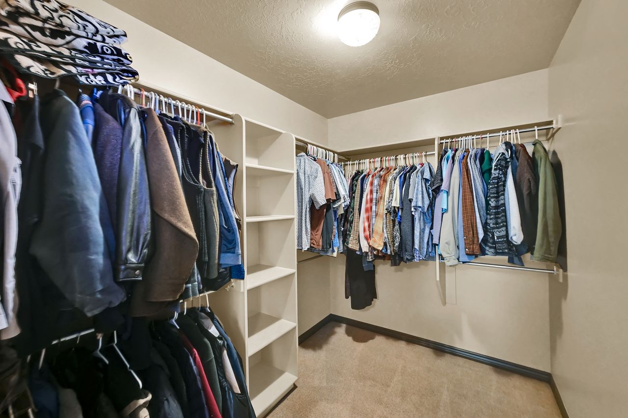 Walk-in closet featuring extensive built-in shelving and multiple clothing rods