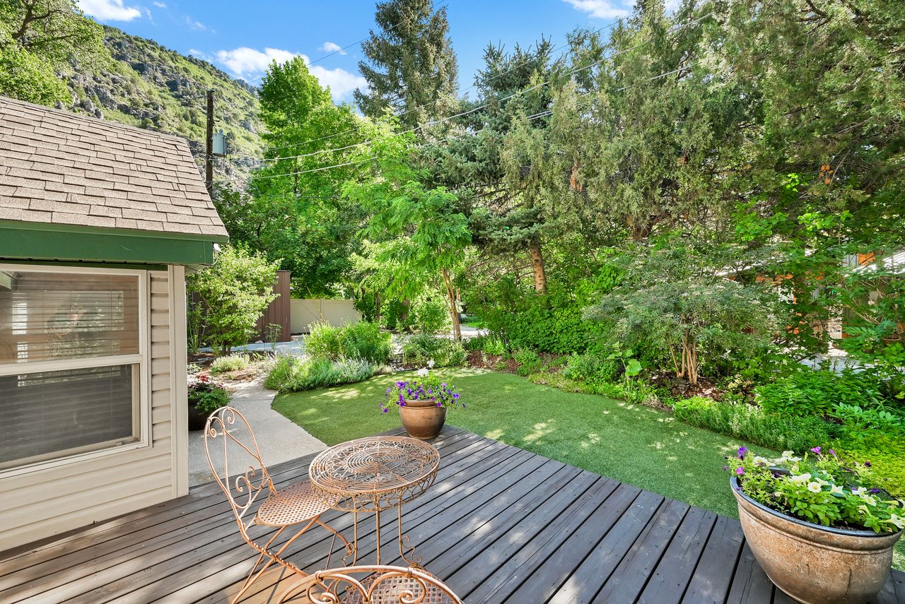 Hardscaping includes a wooden deck, a curved concrete pathway, and a grassy area