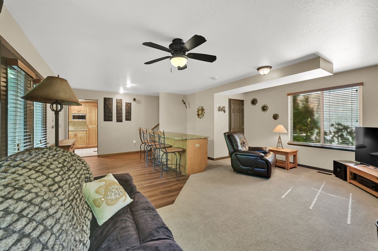 Open-concept living space with a ceiling fan, recessed lighting, and a breakfast bar featuring a light-toned countertop