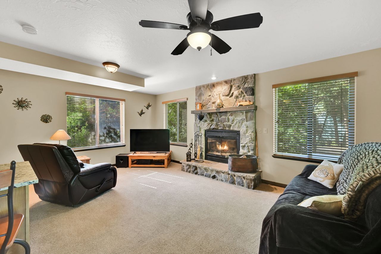 Living area featuring a stone-clad fireplace with a wood mantel, a ceiling fan, and recessed lighting