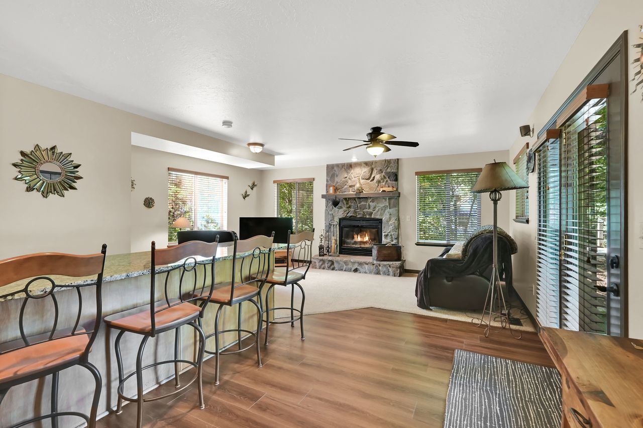 Living area featuring a stone-faced fireplace with a mantel, wood-finish flooring, and a breakfast bar with a light-toned countertop