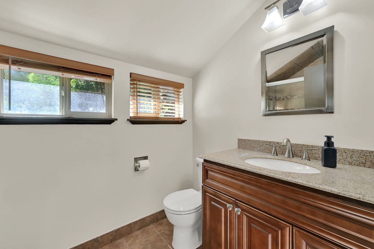Bathroom featuring a wood-finish vanity with a light-toned countertop, an undermount sink, and a brushed nickel faucet