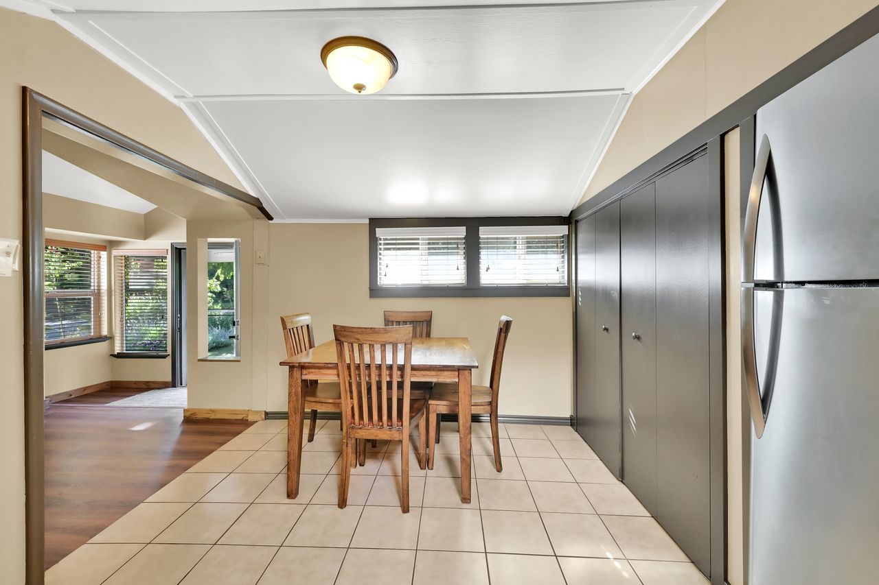 Dining area featuring light-toned tile flooring, a built-in storage wall with dark paneled doors, and a ceiling-mounted light fixture