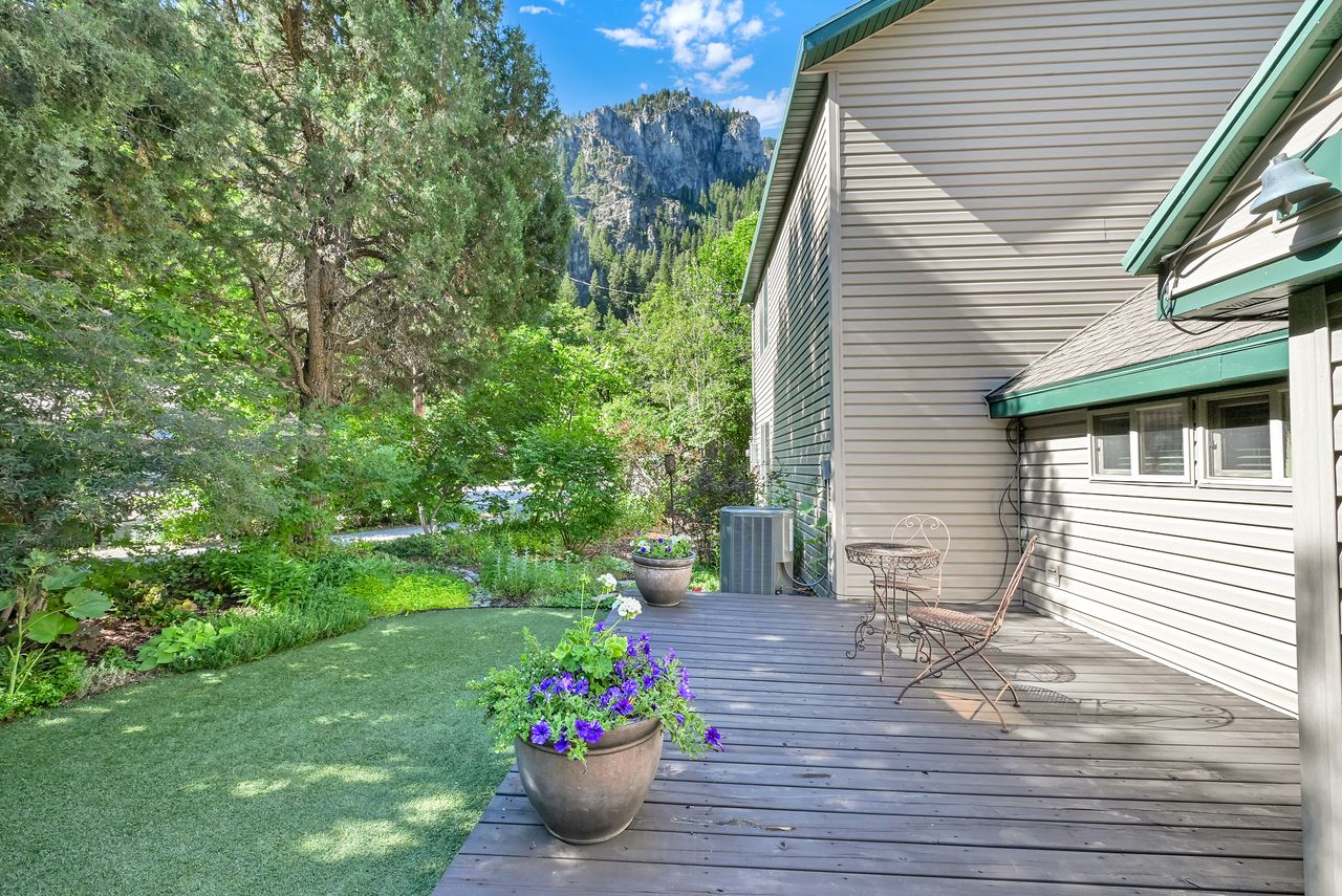 Expansive wooden deck with a built-in outdoor light fixture, siding exterior, and a manicured artificial turf lawn
