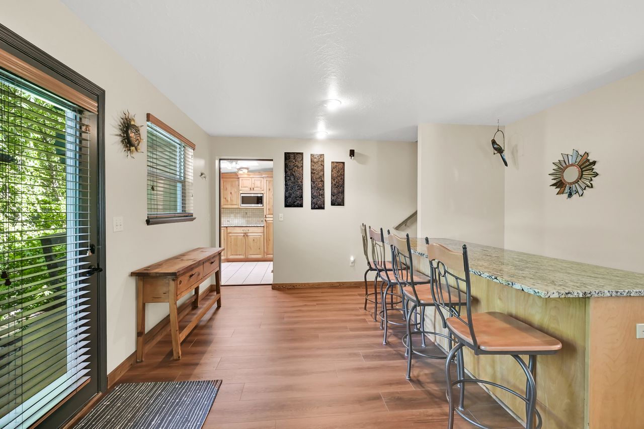 Spacious recreation area featuring a built-in bar with a stone-finish countertop, wood-finish flooring, a large glass-paned door, and a built-in wood console table