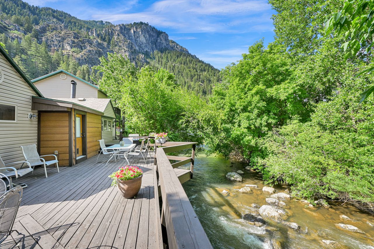 Expansive wood-finish deck overlooking a flowing stream with natural rock formations