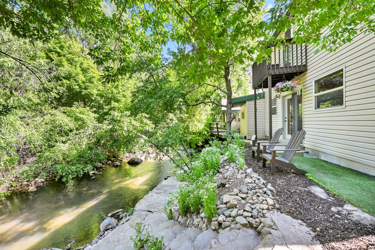 Waterside property featuring a multi-level deck, a private ground-level patio, and stone steps descending to the water's edge