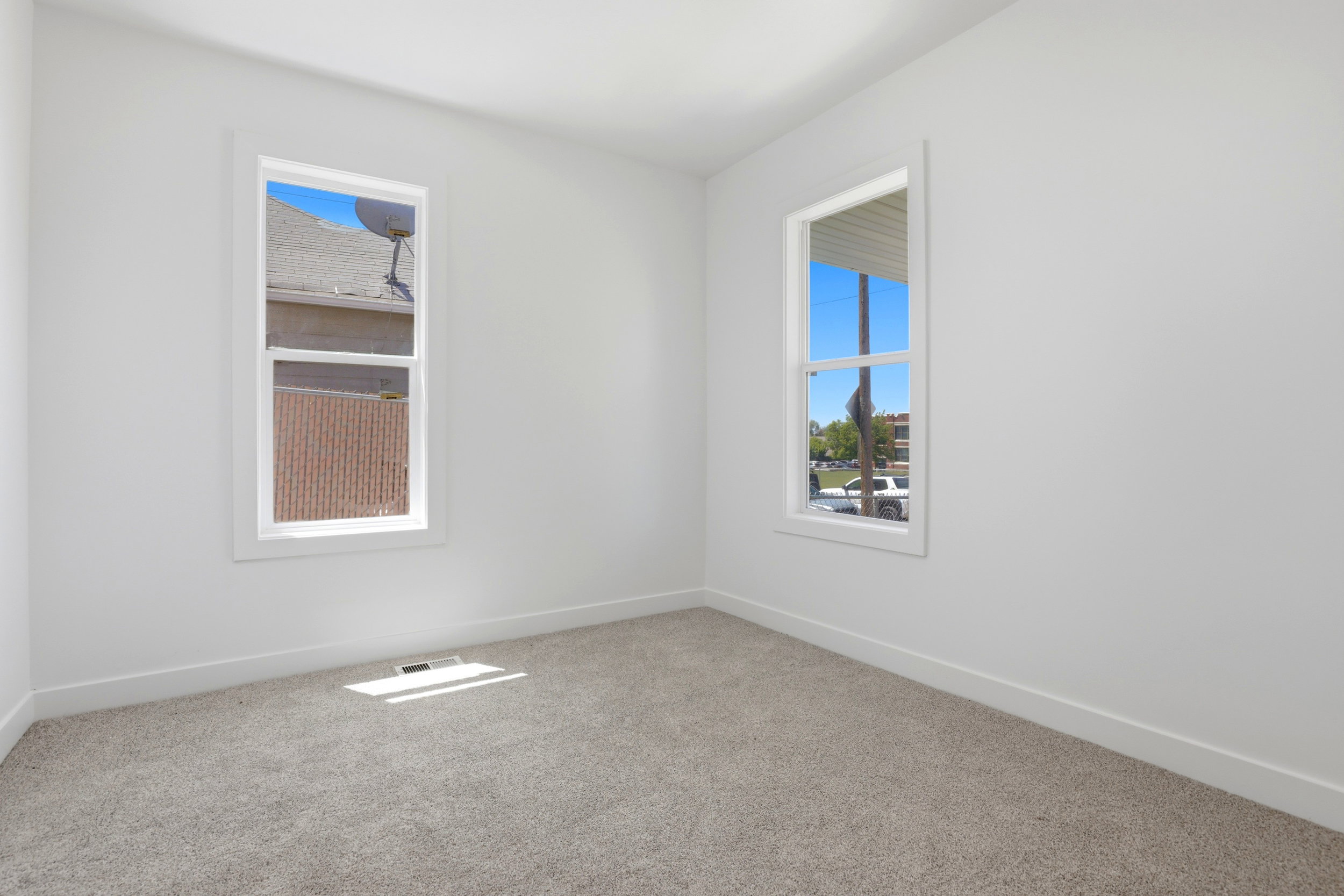 Carpeted room featuring two white-trimmed windows, neutral wall paint, and white baseboards