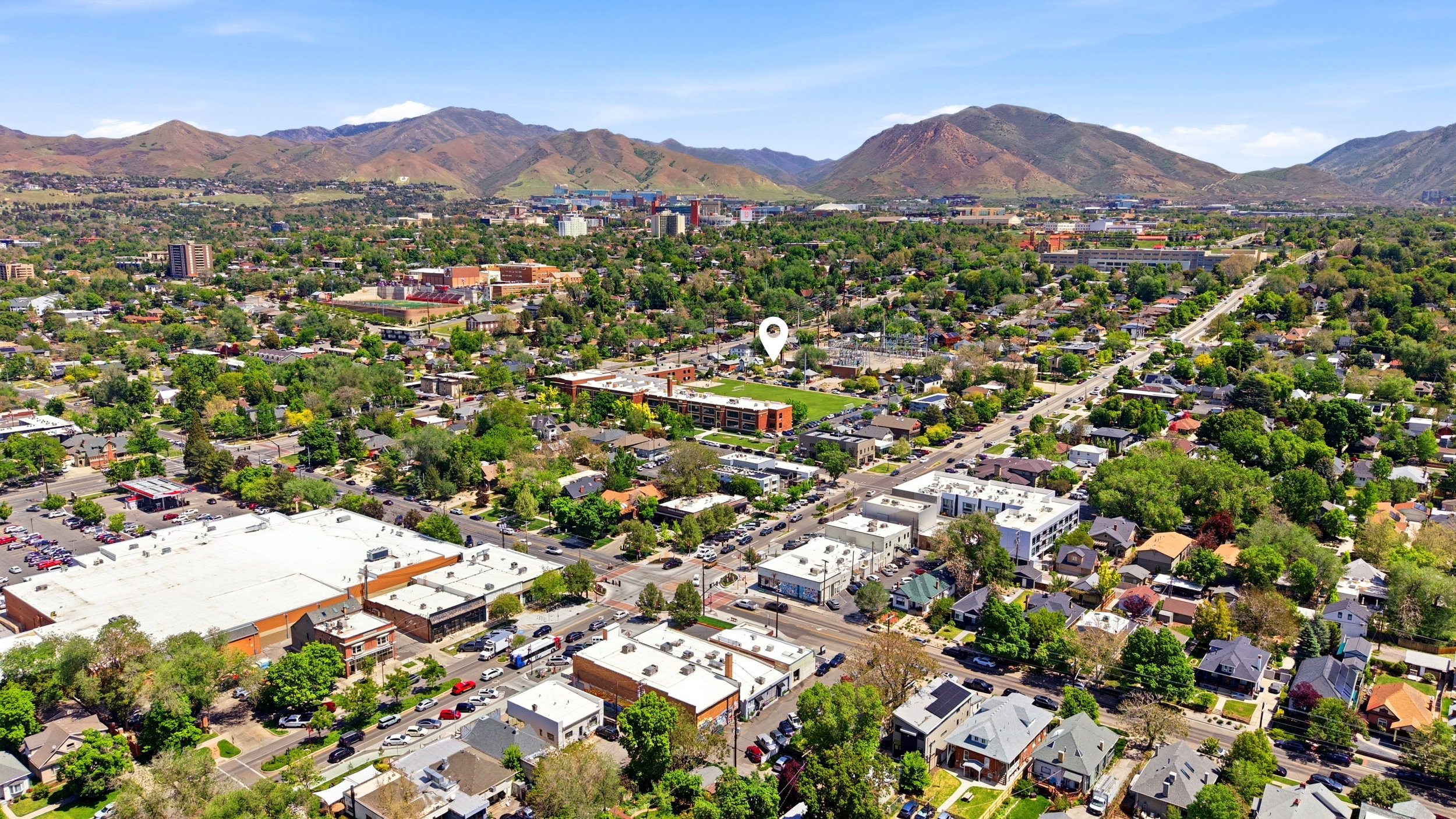 Expansive aerial perspective showcasing a residential and commercial district with distant mountains