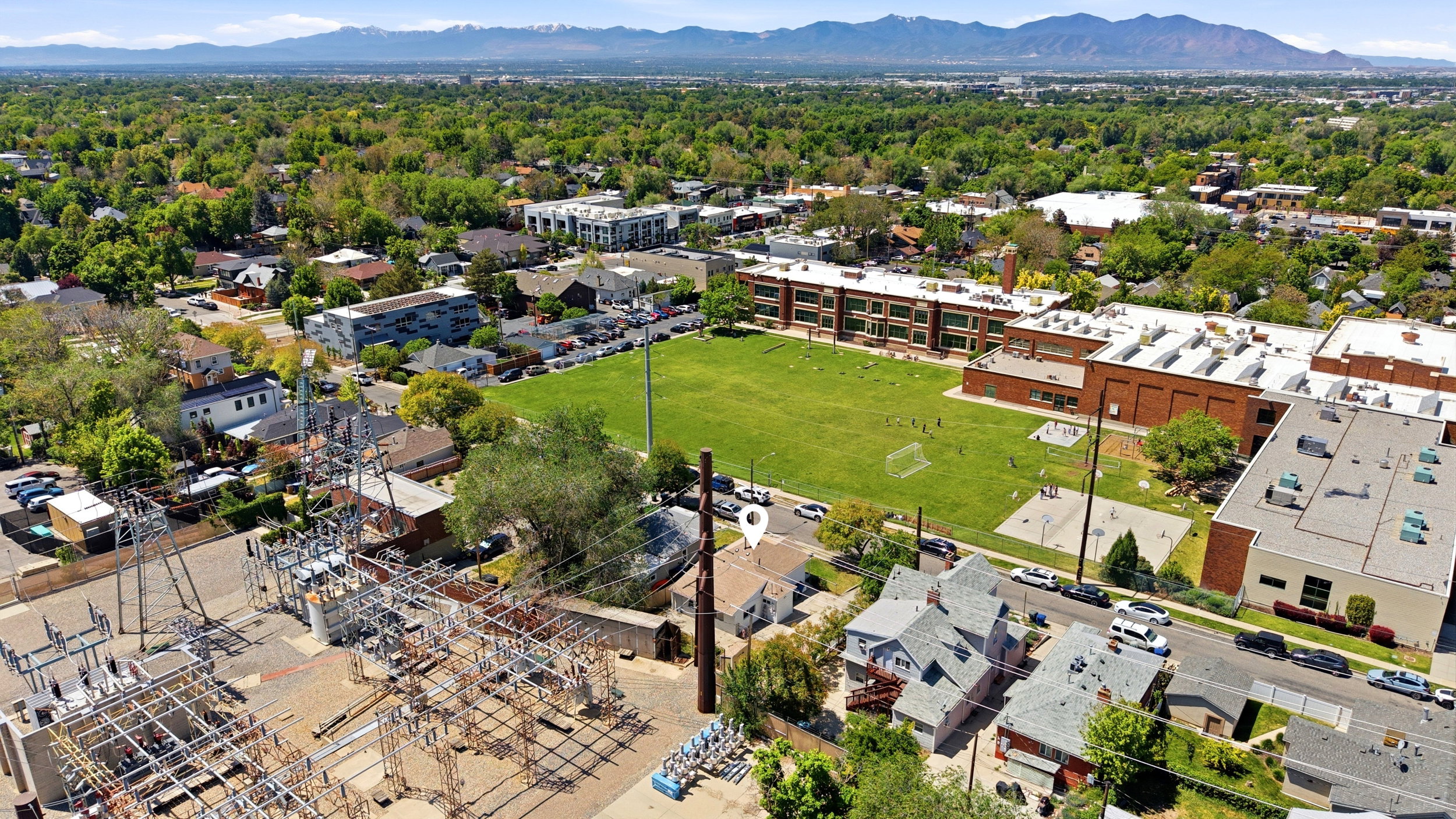 Aerial perspective of a residential neighborhood with a large institutional building and green playing field