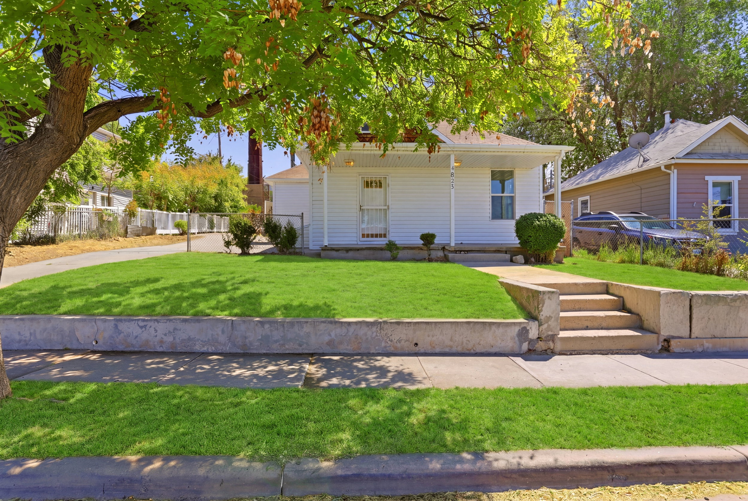 White exterior residence with a covered front porch and a prominent mature tree